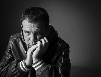 Portrait of man sitting against gray wall