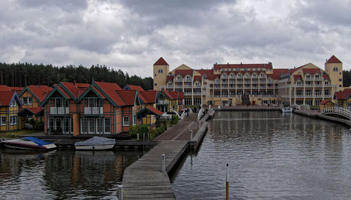 Buildings by river against sky in city