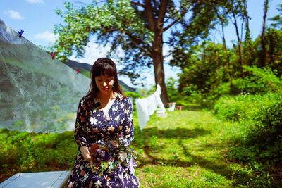 Woman holding bouquet while sitting in park