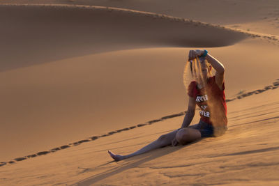 Girl picking sand while sitting at desert