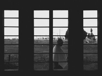 Rear view of silhouette people looking through window