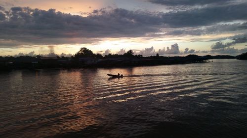 Silhouette man on boat against sky during sunset