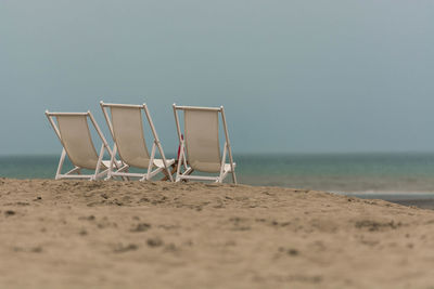 Chairs on beach against sky