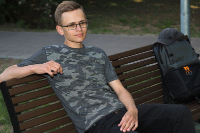 A young man sits on a bench in the shade in summer. high quality photo