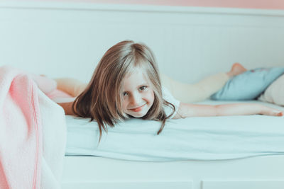 Portrait of cute girl lying on bed at home
