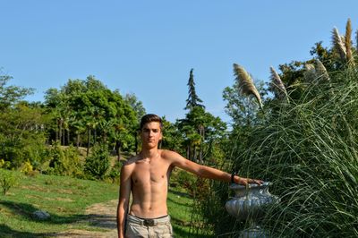 Portrait of shirtless young man standing at park