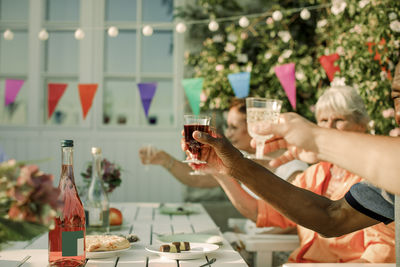Men and women raising toast while sitting at dining table in retirement home