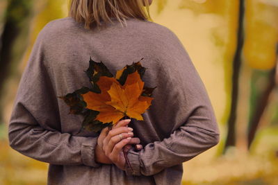 Rear view of person holding yellow flower