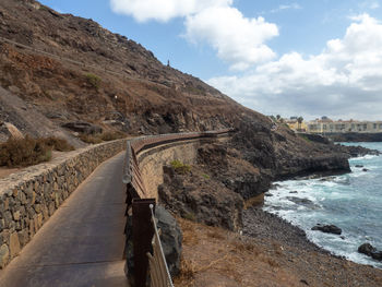 Road leading towards mountain against sky