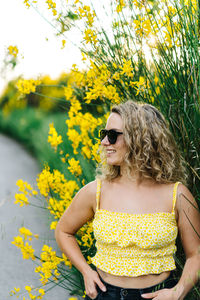 Midsection of woman with yellow flowers against plants
