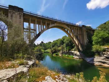 Arch bridge over river against sky