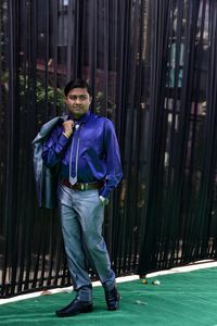 Full length of young man standing by curtains