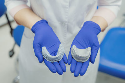 Midsection of doctor holding dentures