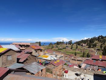 High angle view of houses in town against blue sky