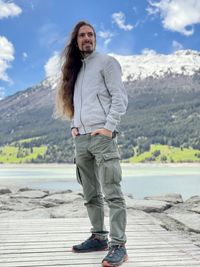 A young long-haired man posing in front of the lago di resia.