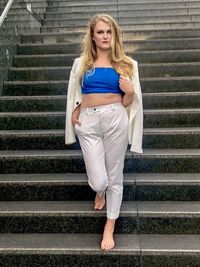 Full length portrait of beautiful woman standing on staircase