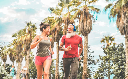 Smiling friends jogging against palm trees