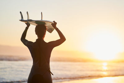 Cropped hand of woman with arms raised against sky during sunset