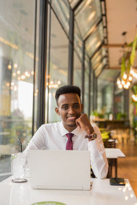 Portrait of young man using mobile phone while sitting in cafe