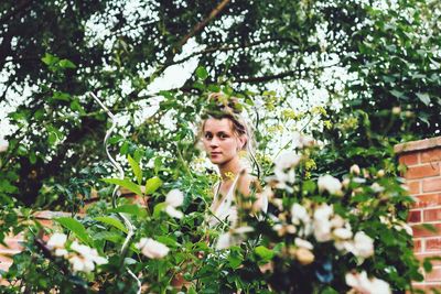 Portrait of woman standing amidst trees