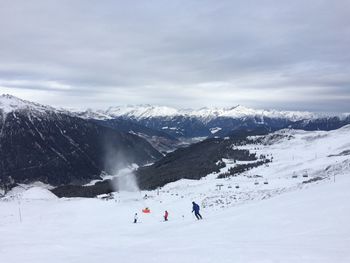 People skiing on snowcapped mountain against sky