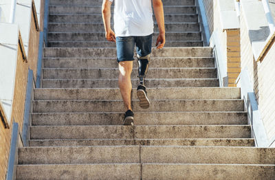 Young man with leg prosthesis walking upstairs