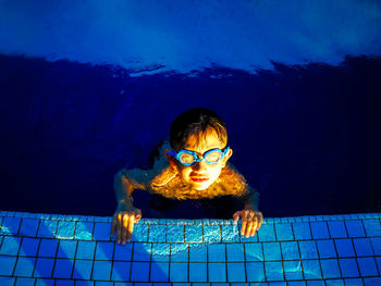 Portrait of boy swimming in water against blue sky