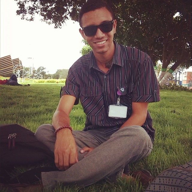 young adult, person, lifestyles, casual clothing, leisure activity, looking at camera, portrait, young men, sitting, front view, sunglasses, three quarter length, grass, smiling, standing, relaxation, tree