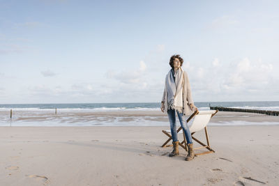 Woman standing next to deckchair on the beach