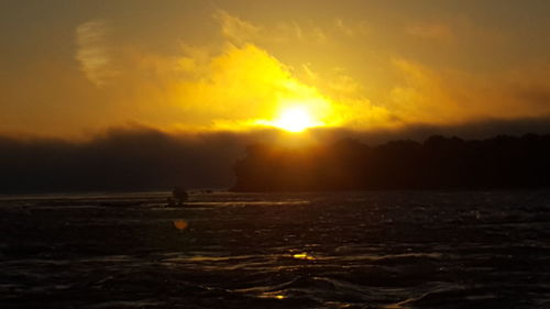 Scenic view of sea against cloudy sky during sunset