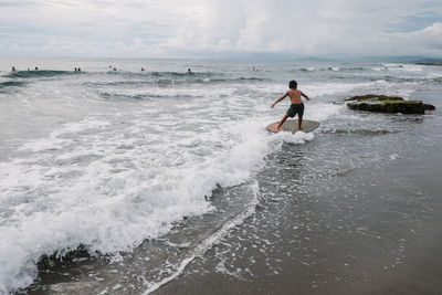 Man surfing in sea against sky