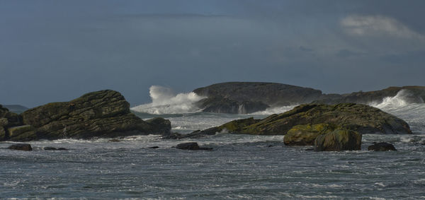 Scenic view of stormy sea and rocks against sky