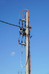 Low angle view of telephone pole against blue sky