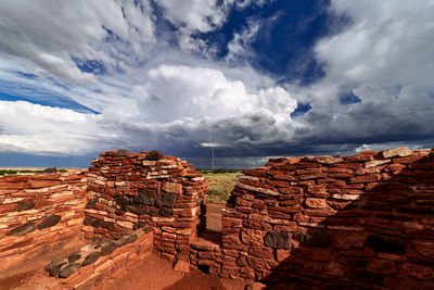 Brick wall against cloudy sky