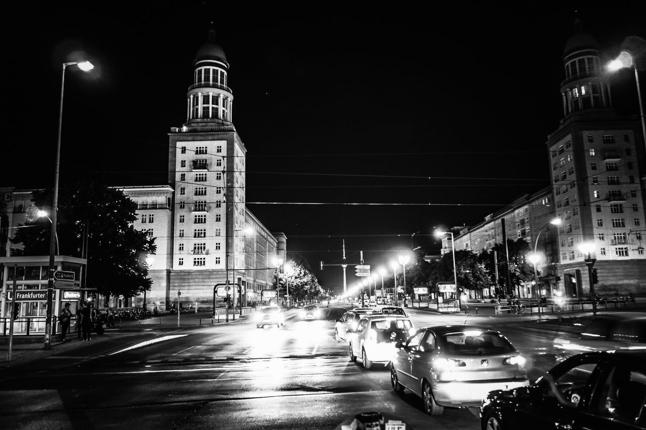 CARS ON CITY STREET BY ILLUMINATED BUILDINGS AT NIGHT