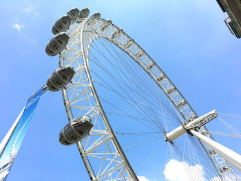 Low angle view of ferris wheel against blue sky