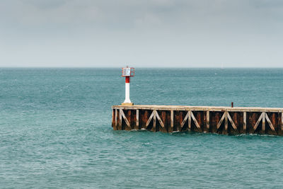 View of lighthouse on pier in sea against sky