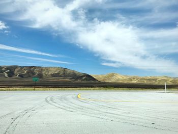 Scenic view of road by mountains against sky