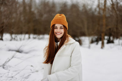 Portrait of smiling young woman standing on snow