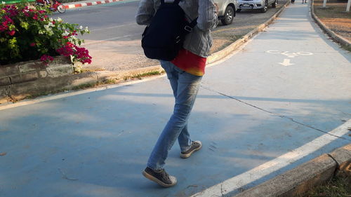 Low section of woman walking on sidewalk in city