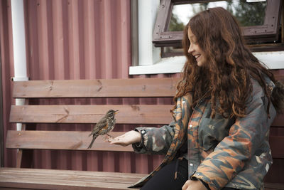 Bird perching on young woman's hand