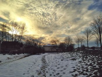 Snow covered field against cloudy sky