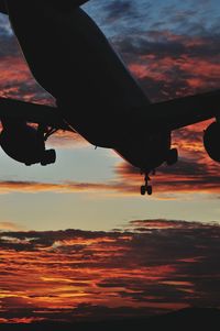 Low angle view of silhouette airplane flying against sky during sunset