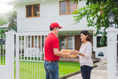 Full length of man holding woman standing against building