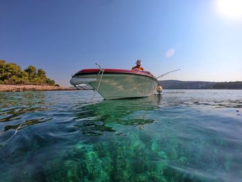 Fishing boat in sea against clear blue sky