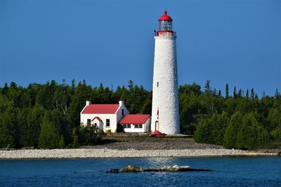 Lighthouse by building against sky