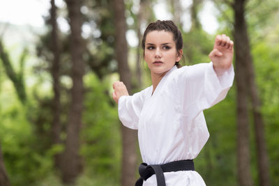 Portrait of young woman standing against trees