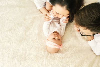 High angle view of parents playing with baby girl lying on bed