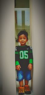 Portrait of smiling boy standing against wall