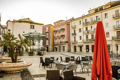 Chairs and tables in restaurant against buildings in city